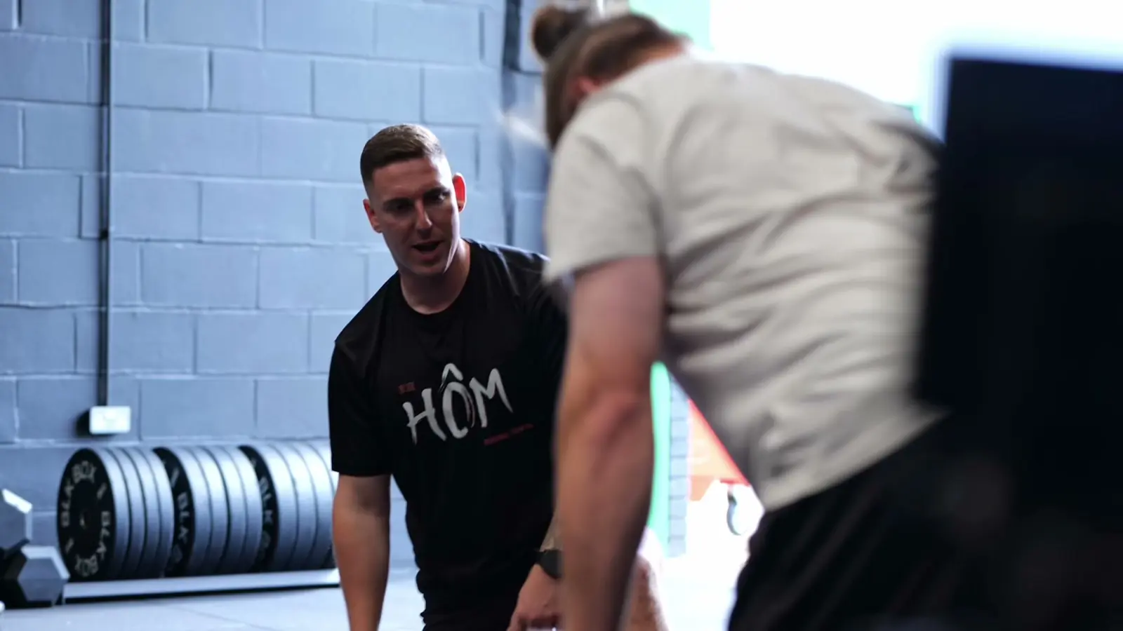 A Hōm coach giving technique cues to a member during a small group personal training session in Milton Keynes