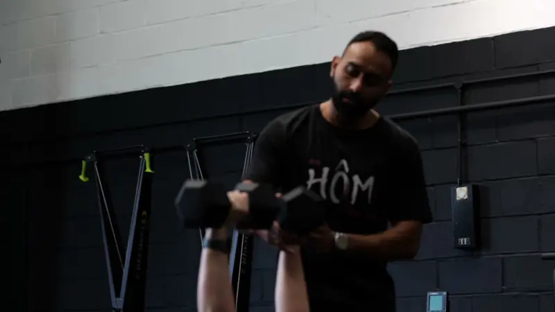 A Hōm coach demonstrating a dumbbell exercise