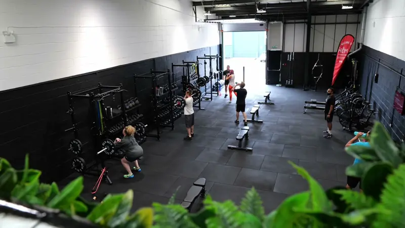Inside Hōm Personal Training in Kiln Farm, Milton Keynes, with racks along a black wall